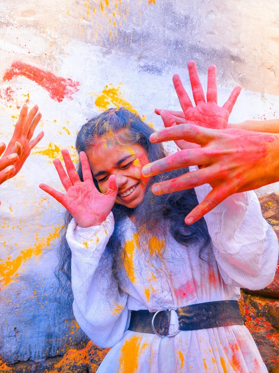 a girl is making hands up with paint on her face