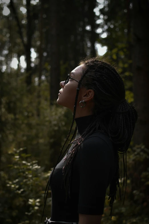 a woman with long dreadlocks standing in the woods