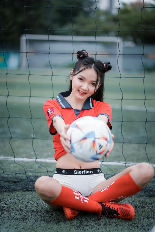 a girl poses as she catches a soccer ball