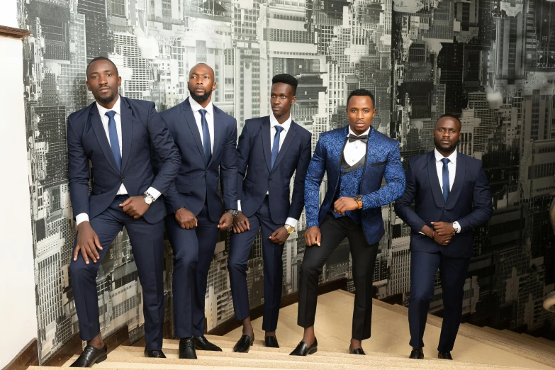 several men in suits, one is standing up and the other two are on stairs