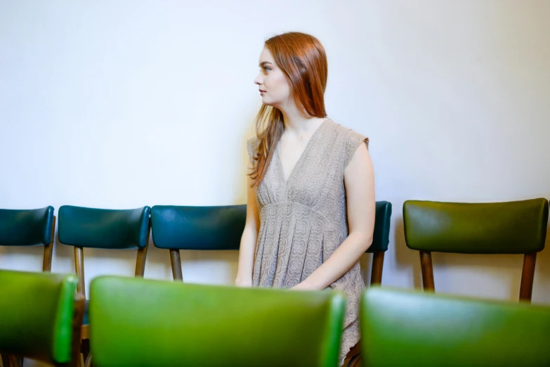 the woman is standing next to rows of green chairs