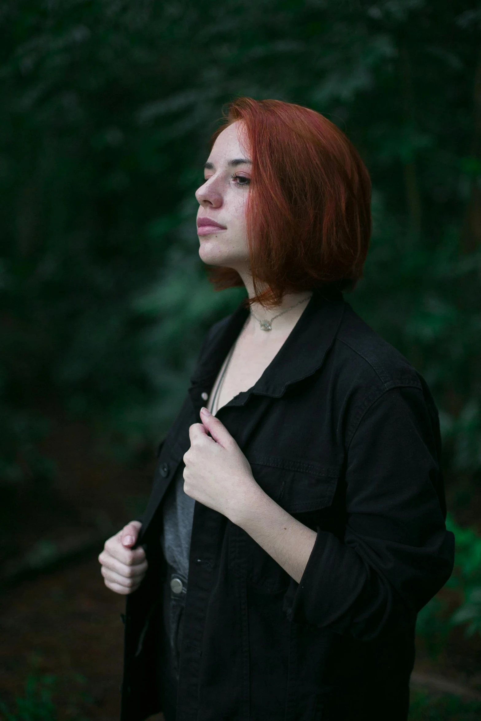 the young woman has red hair and is wearing a black jacket