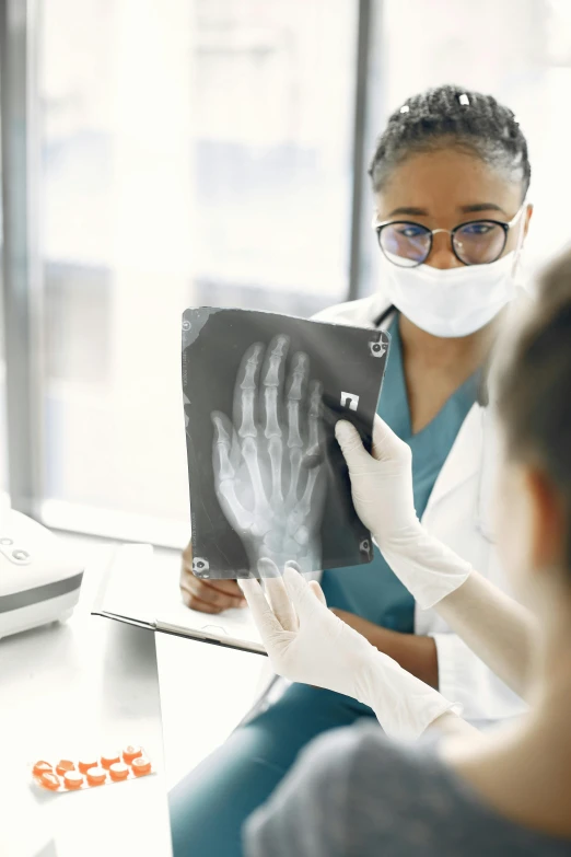 a doctor holding a x - ray print up for a patient