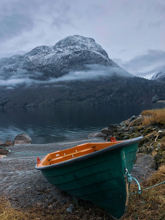 a boat rests on the shore near mountains