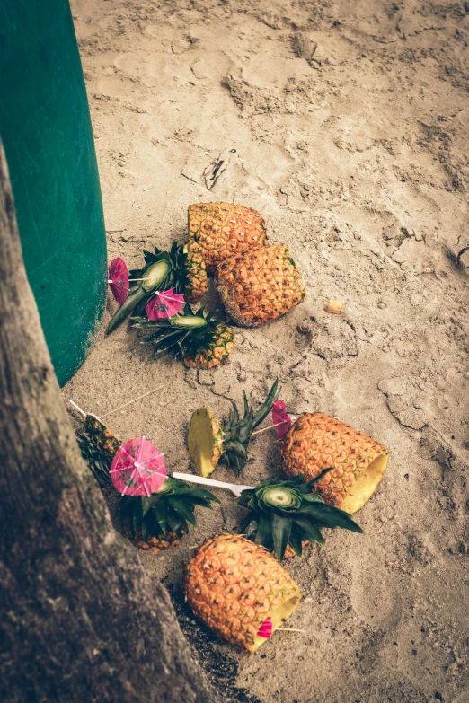 some pineapples on the beach near a trash can