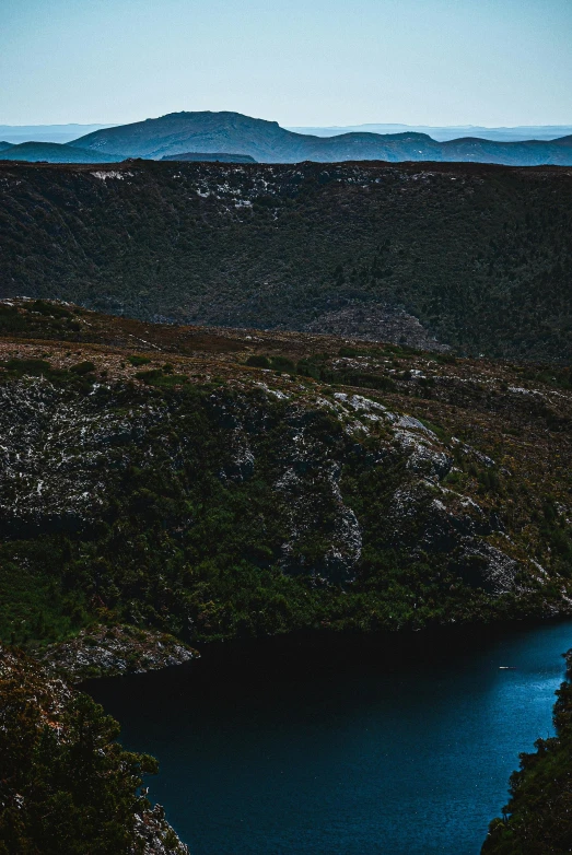 a lake is surrounded by land with mountains in the background