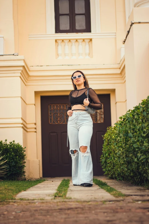a woman with sunglasses is wearing cropped jeans