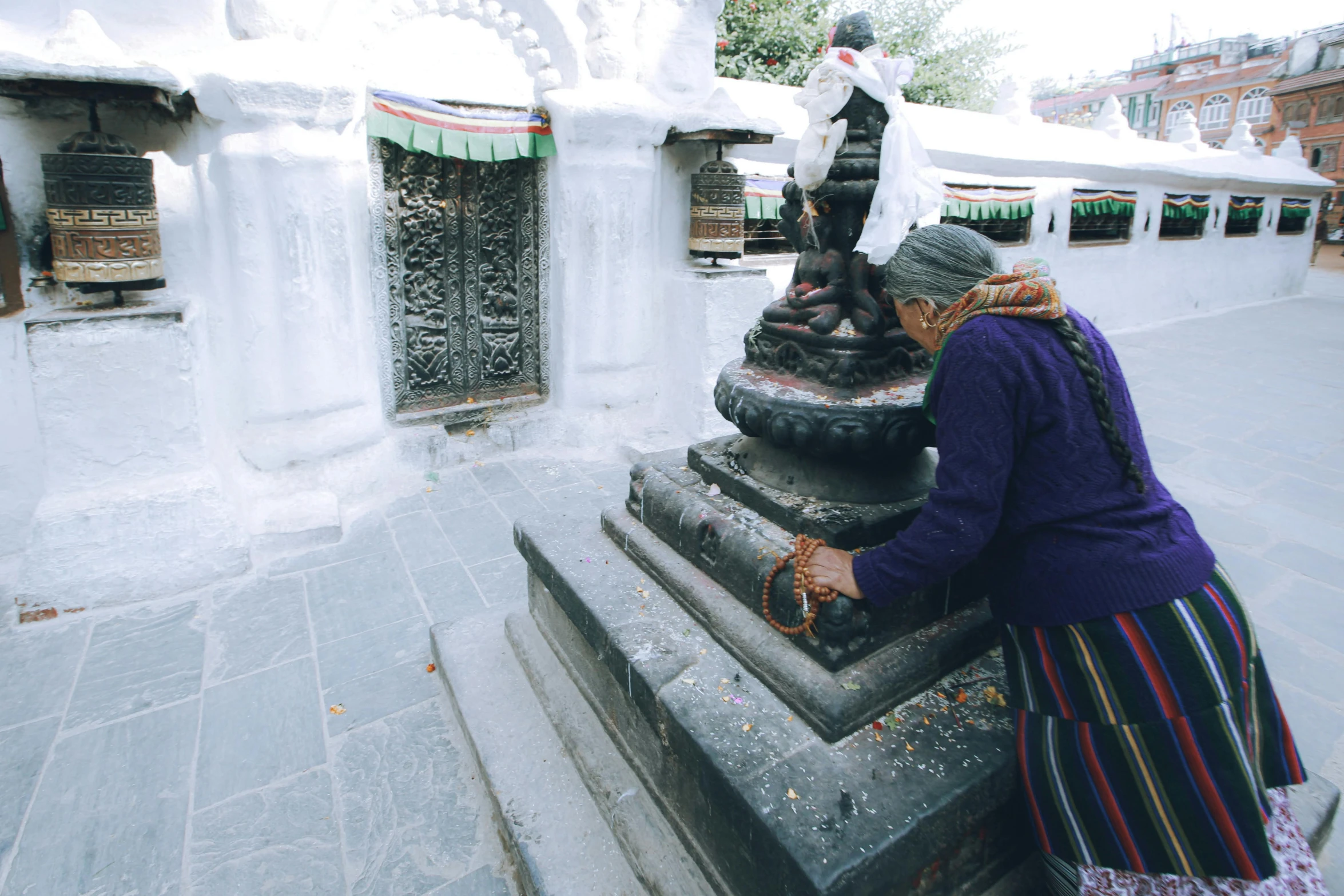 a woman in traditional clothing with a bag looking down at an item