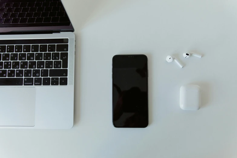 apple mac book, earphones, and keyboard on a desk