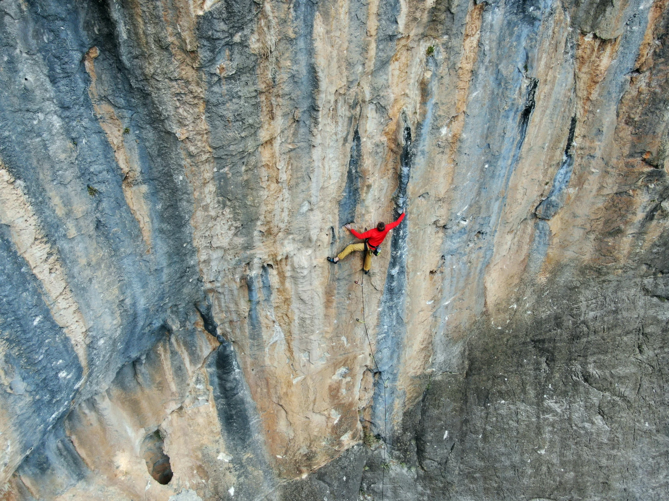 a lone man is on the side of a mountain climb
