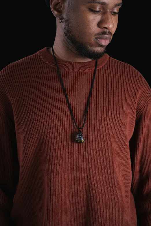 a black man wearing a red sweater with a necklace on