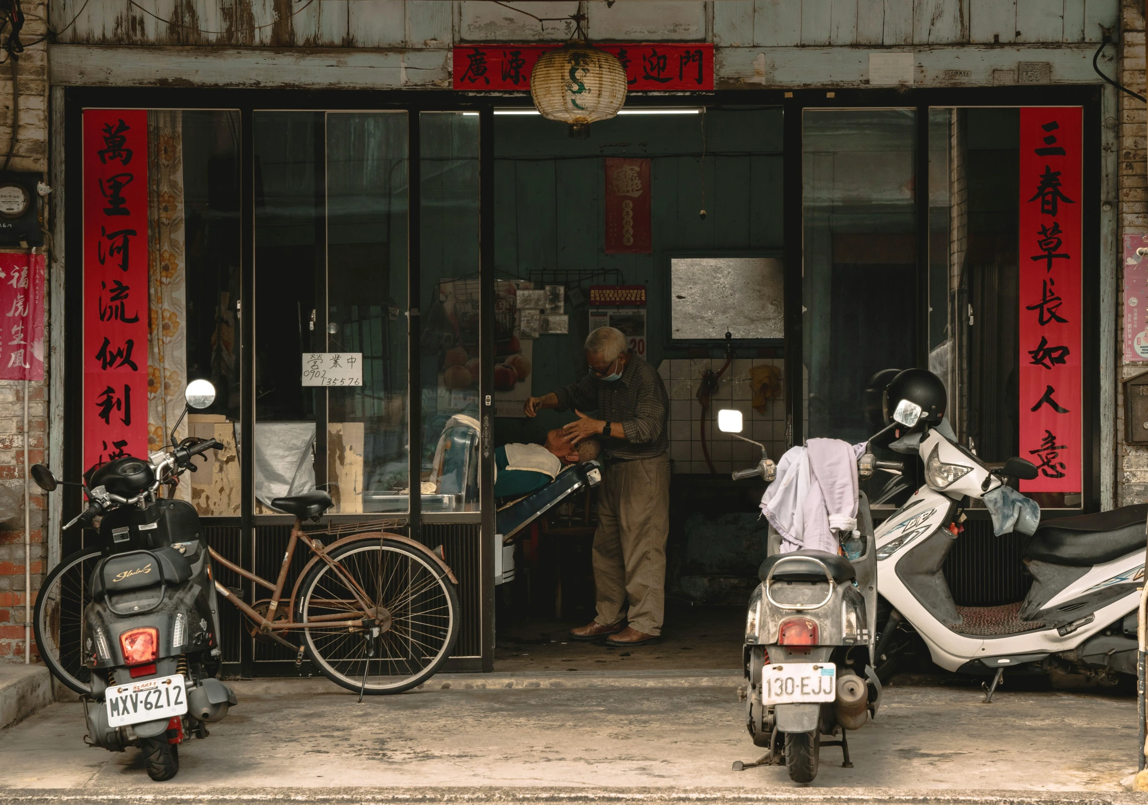 two mopeds and one scooter parked in front of a building with red signs on the side