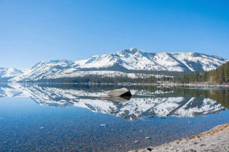 a mountain range rises in the distance from a lake