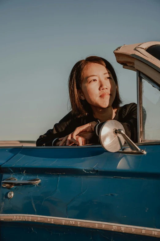 a woman sitting in the back seat of a blue convertible