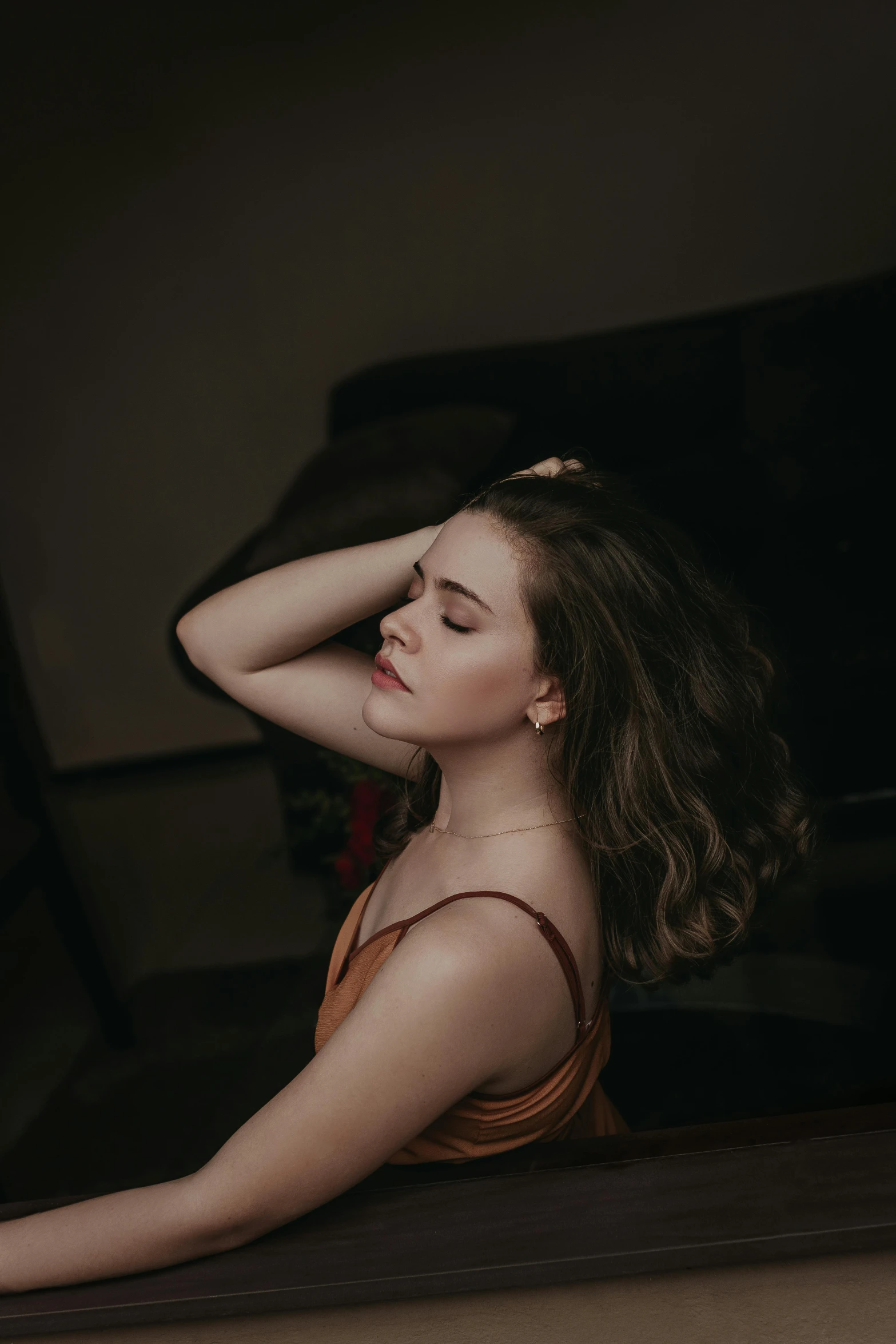 a young woman is sitting and posing in a dark room