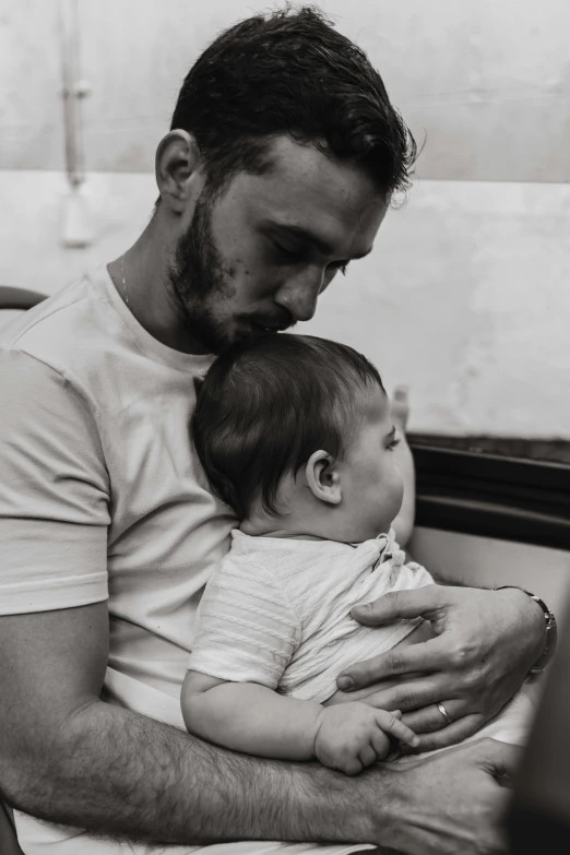 a man holds a baby as he looks at his phone