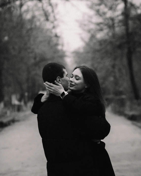 couple emcing each other on the street with trees behind