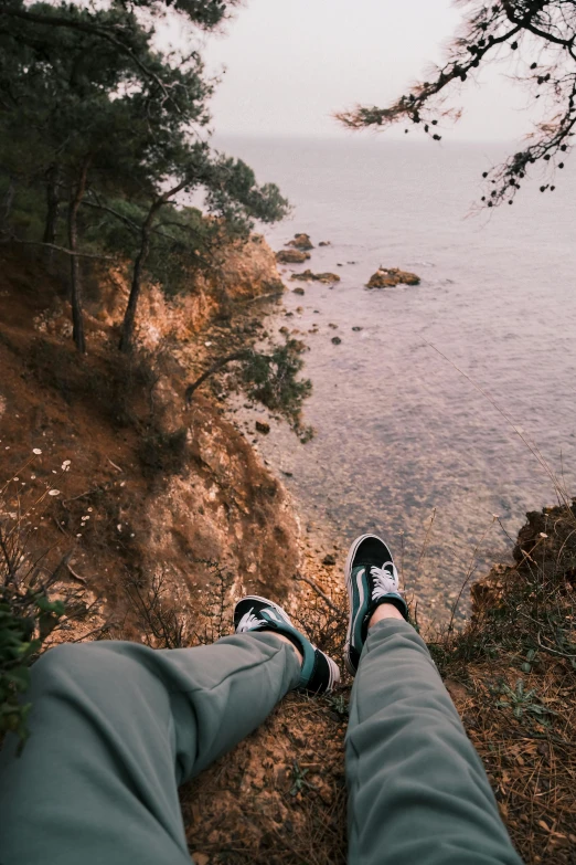 the feet of a person standing at the edge of a cliff overlooking a river