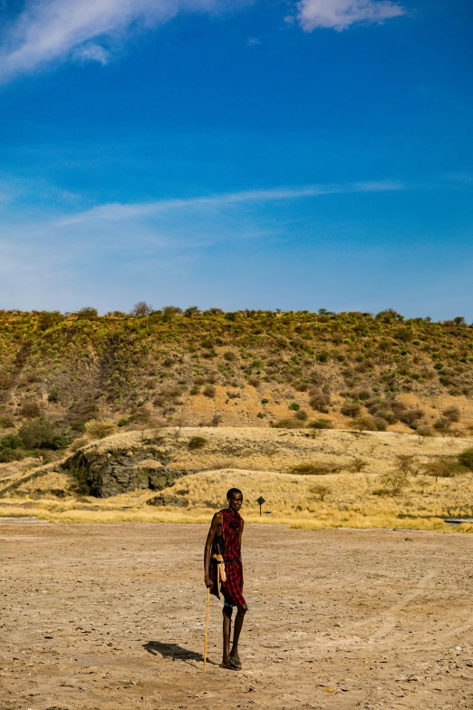 the man is wearing a red suit and standing in the dirt