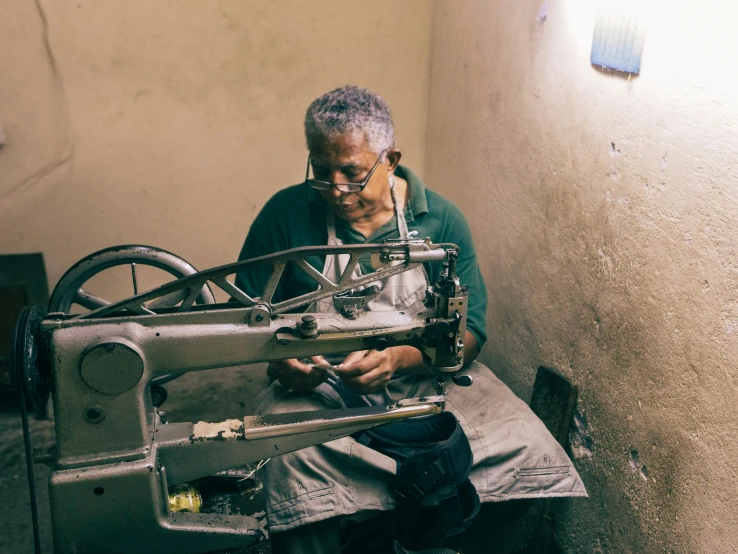 an older man is sewing on a metal frame