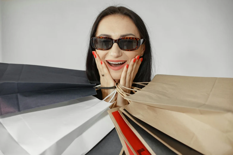 an attractive woman smiles with her hands on the face behind a bag