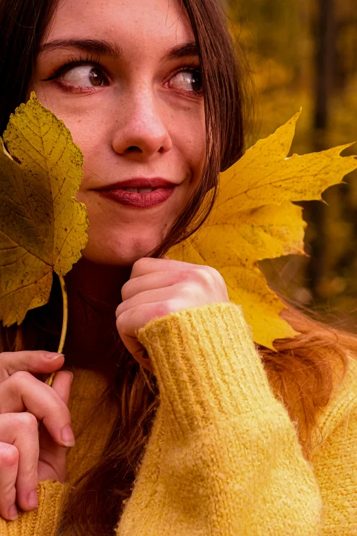 a woman is holding up a leaf while posing for a picture