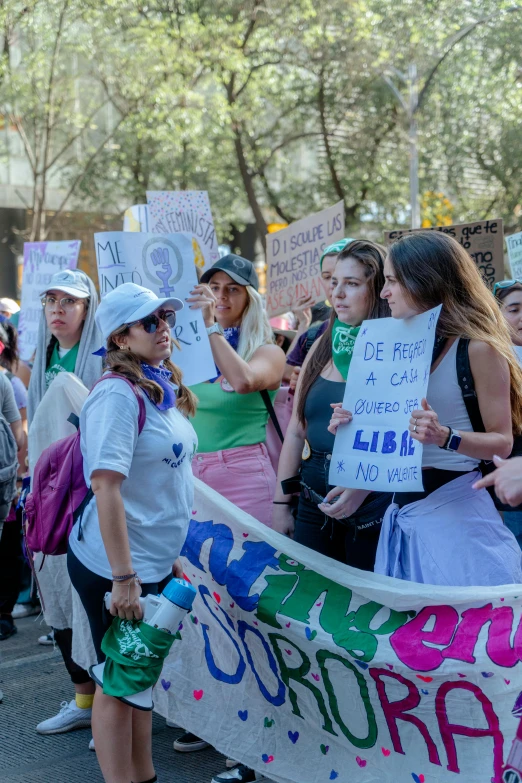 a group of people gathered on a city street with one woman holding a sign