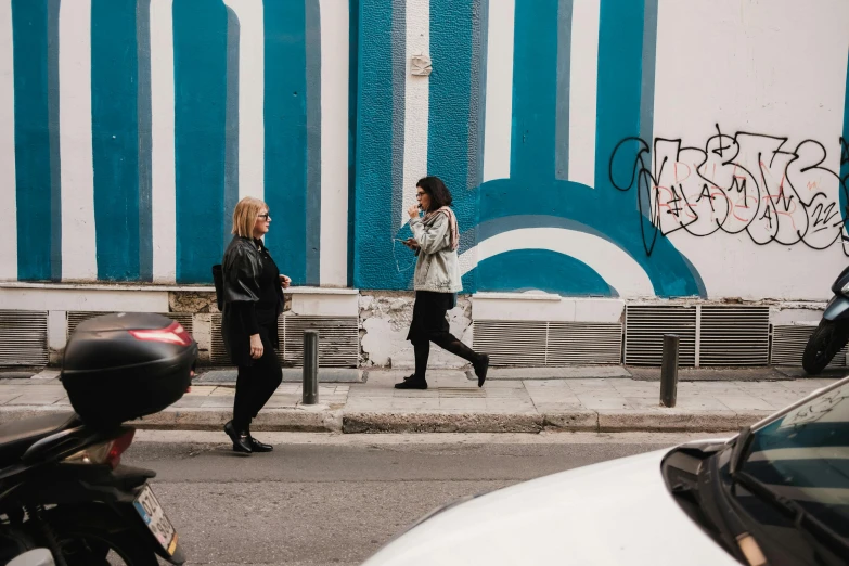 a woman walks down a city street while another watches