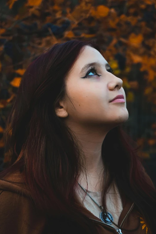 a woman with long hair in brown jacket looking upward