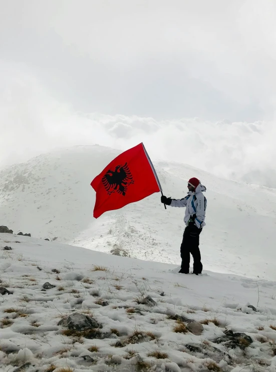 a person is standing on a snowy hill holding up a flag