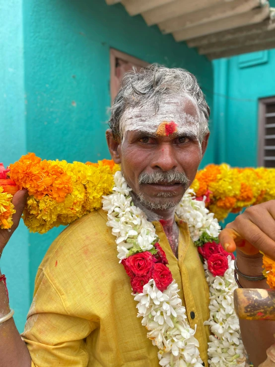 a man holding up flowers next to a blue building