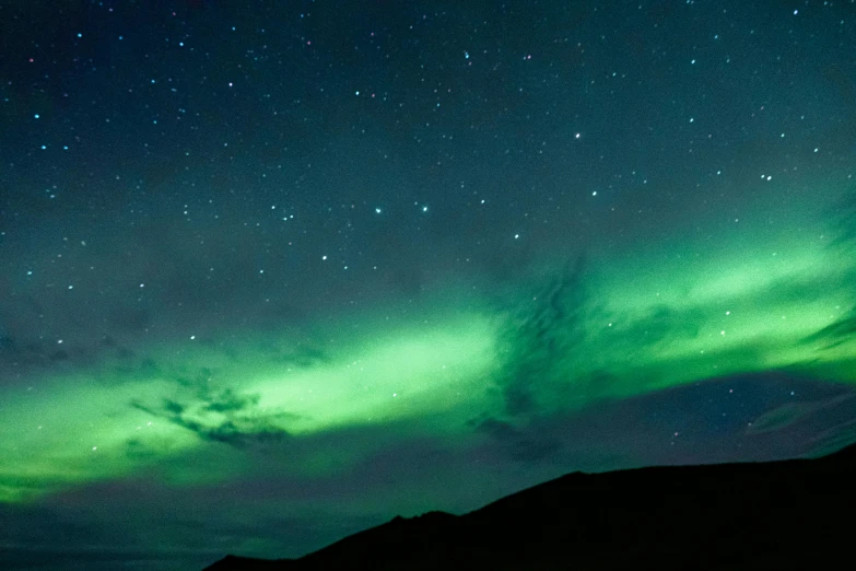 a very long bright green aurora bore is lit in the night sky