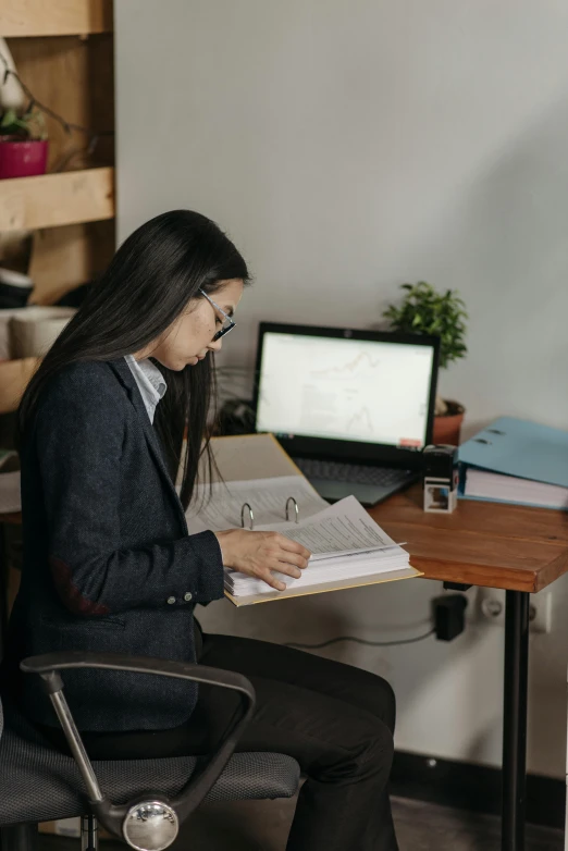 a woman sitting at a desk working on a laptop