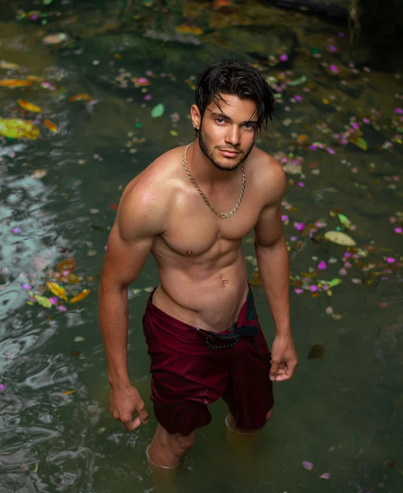 a man walking into the water shirtless and wearing 