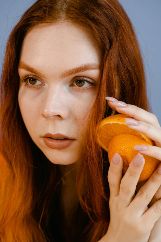 a woman is holding an orange next to her face