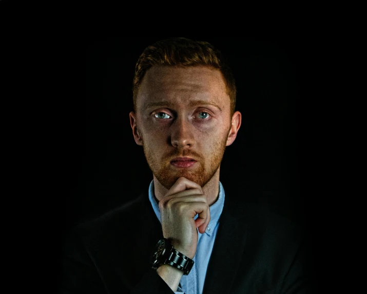 a man in a blue shirt with his hands under his chin