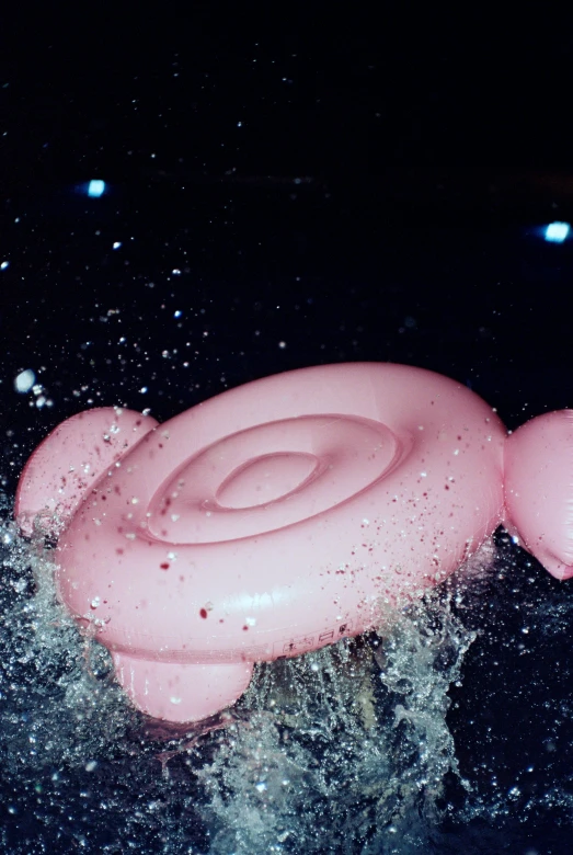 a pink toy floating on the surface with some water bubbles