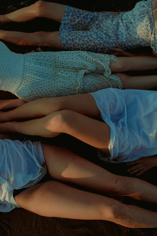 the three women lie side by side wearing white underwear