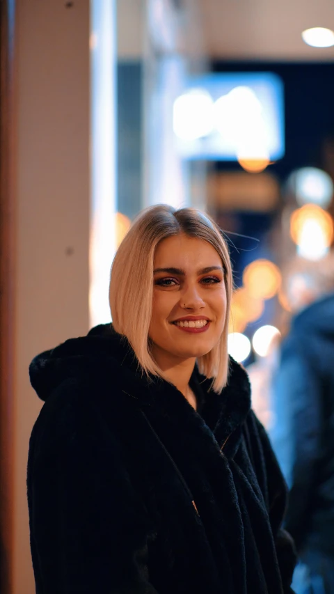 smiling woman in black coat by windows