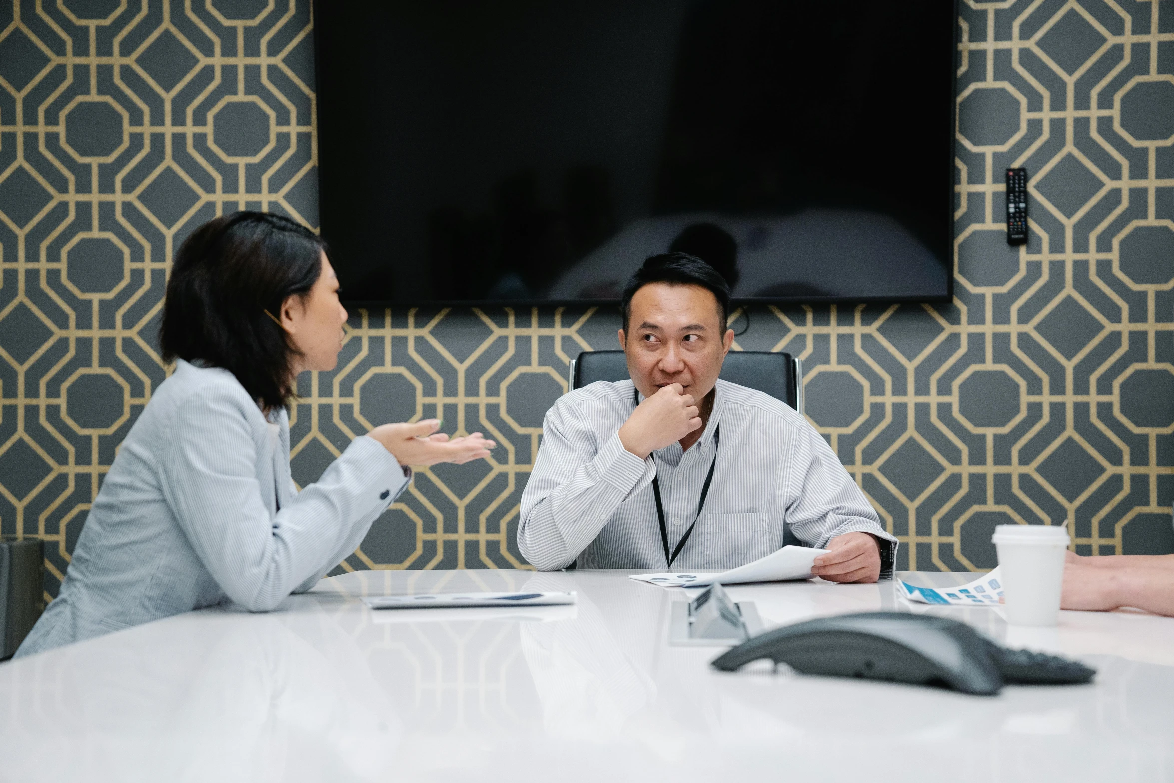 two people seated at a round table and one person is pointing to soing