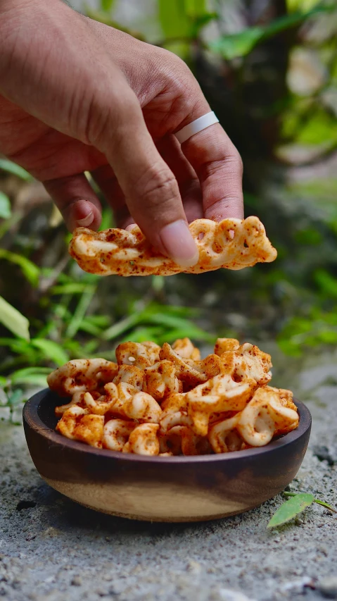 a person reaching for a piece of food in a bowl