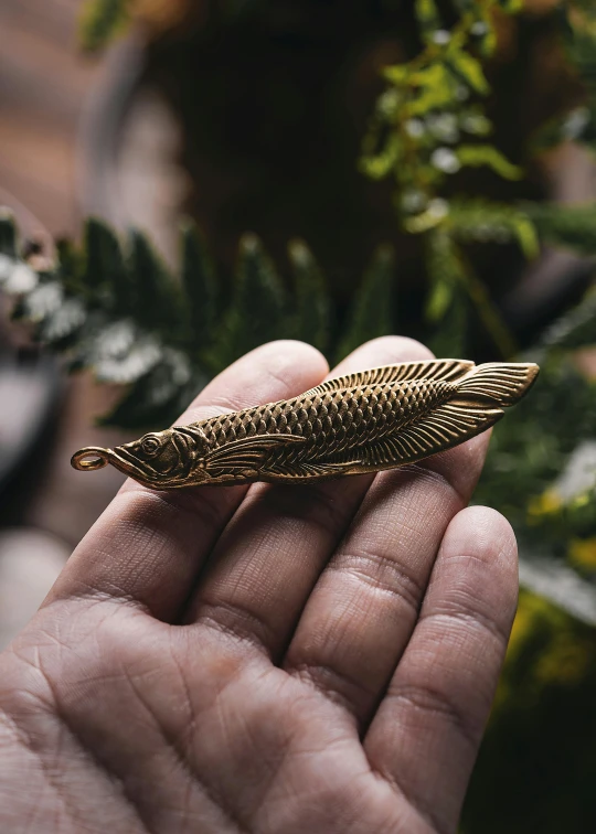 a person holds a small feather brooch