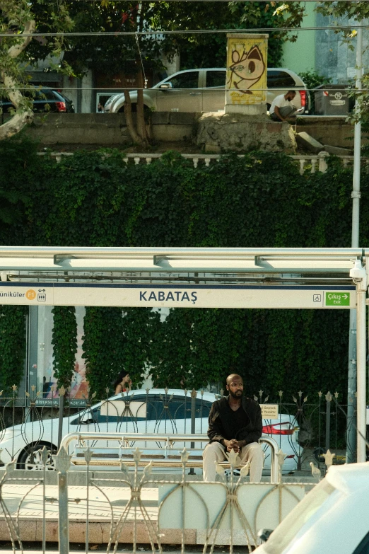 a man sits on top of a fence in front of cars