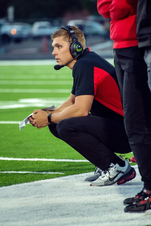 a young man sitting on the sideline wearing headphones