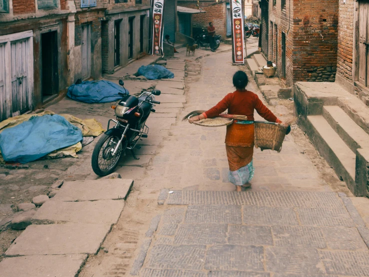 the woman walks up the street carrying a basket