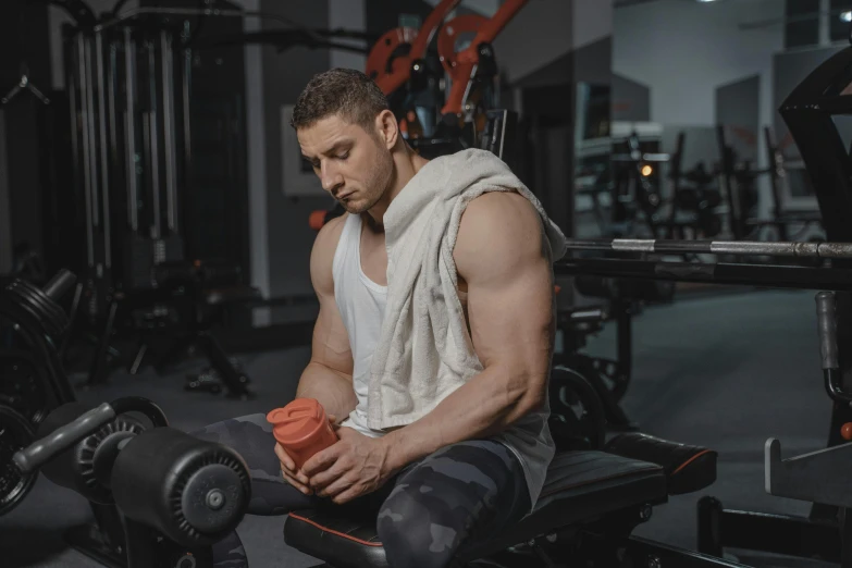 a young man sitting on a bench in a gym