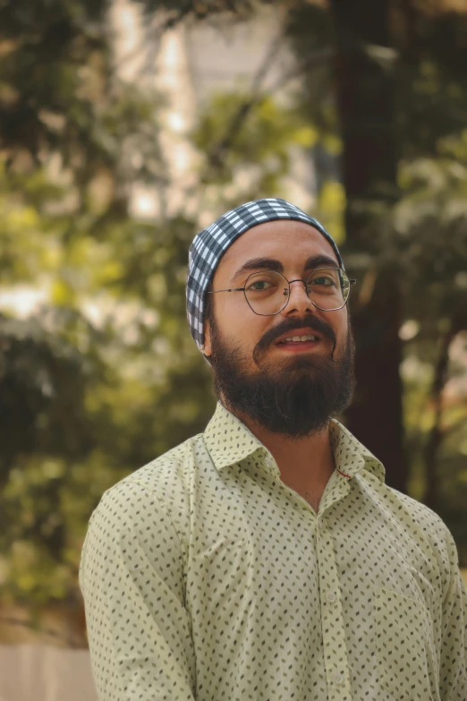 a man in a green shirt and glasses standing in the forest