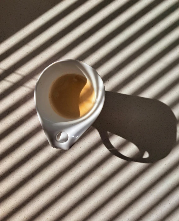 coffee in a mug sits casting a shadow on a table