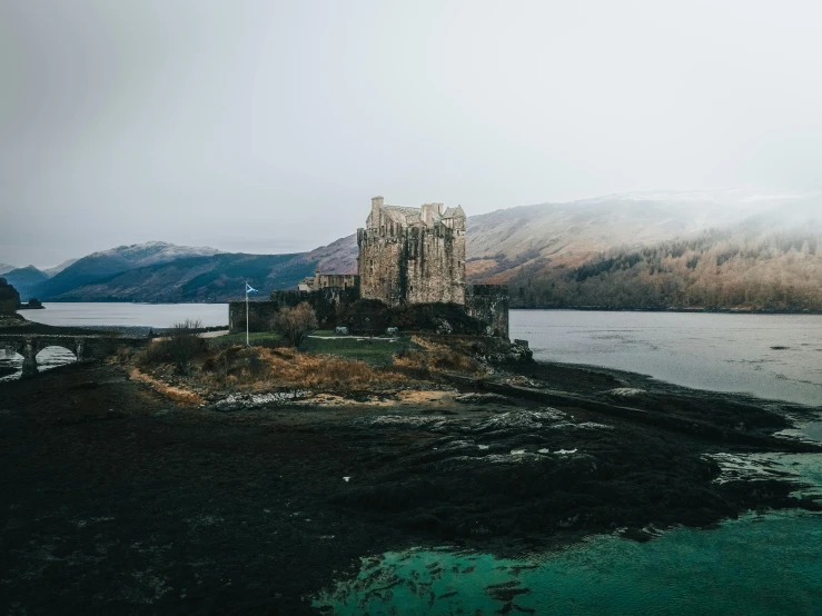 a castle is perched on an island by the water