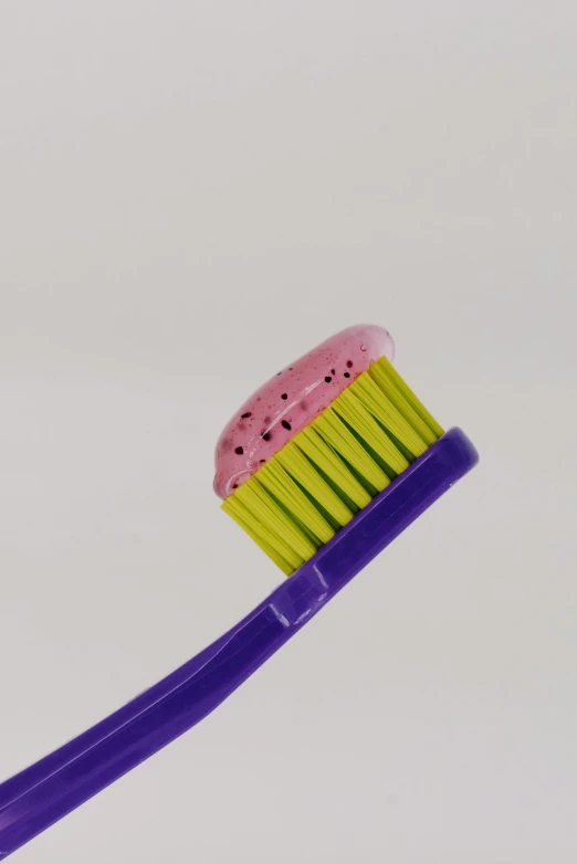 a purple toothbrush with a pink and yellow bristles